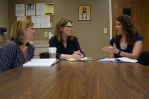 Three women sitting together in discussion at a table.
